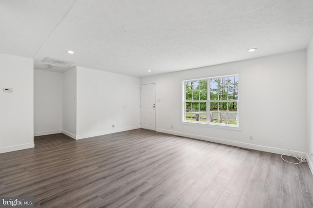 spare room featuring recessed lighting, wood finished floors, and baseboards