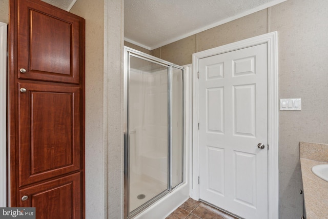 full bathroom featuring ornamental molding, vanity, a shower stall, a textured ceiling, and tile patterned floors