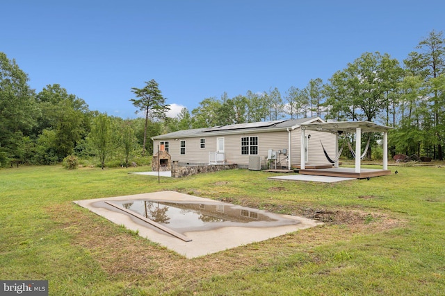 rear view of house with a deck, central AC, a lawn, and roof mounted solar panels