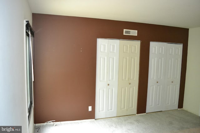 unfurnished bedroom featuring carpet flooring and two closets