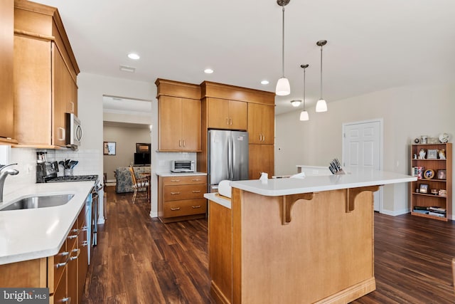 kitchen with stainless steel appliances, hanging light fixtures, sink, and a kitchen island