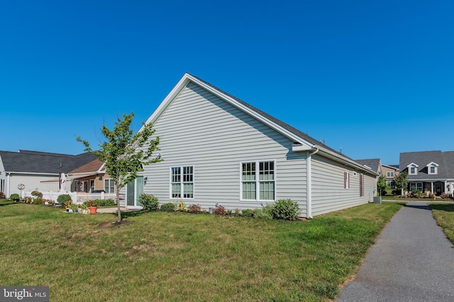 view of side of home with covered porch and a lawn