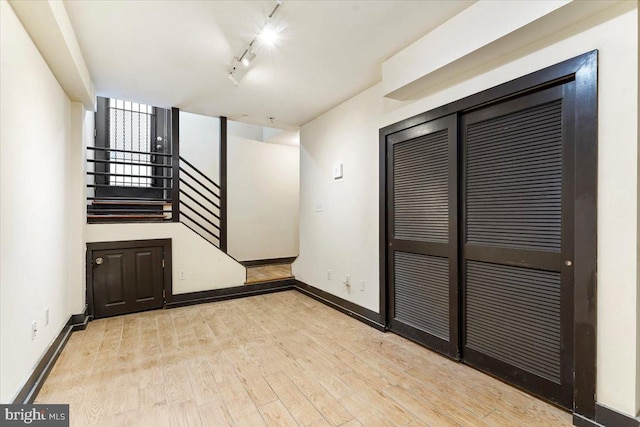 empty room with track lighting and light hardwood / wood-style floors