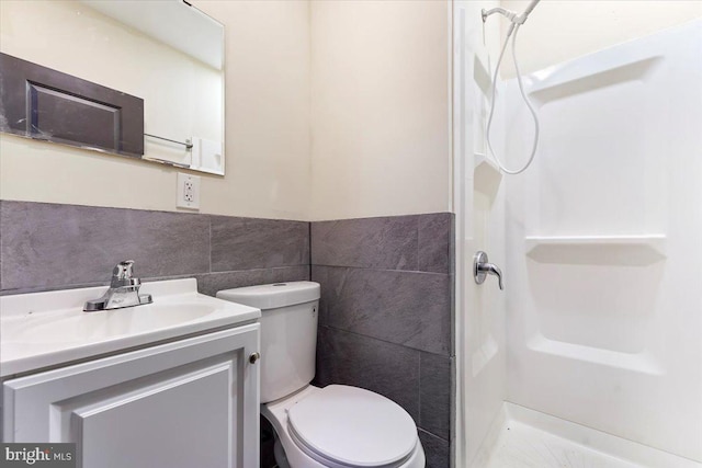 bathroom with tile walls, toilet, and vanity