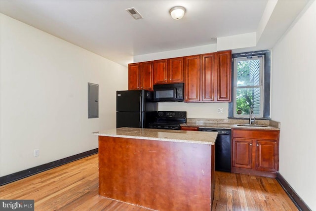 kitchen featuring light wood-type flooring, light stone counters, electric panel, black appliances, and sink