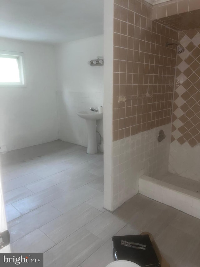 bathroom featuring tiled shower, sink, toilet, and tile patterned flooring