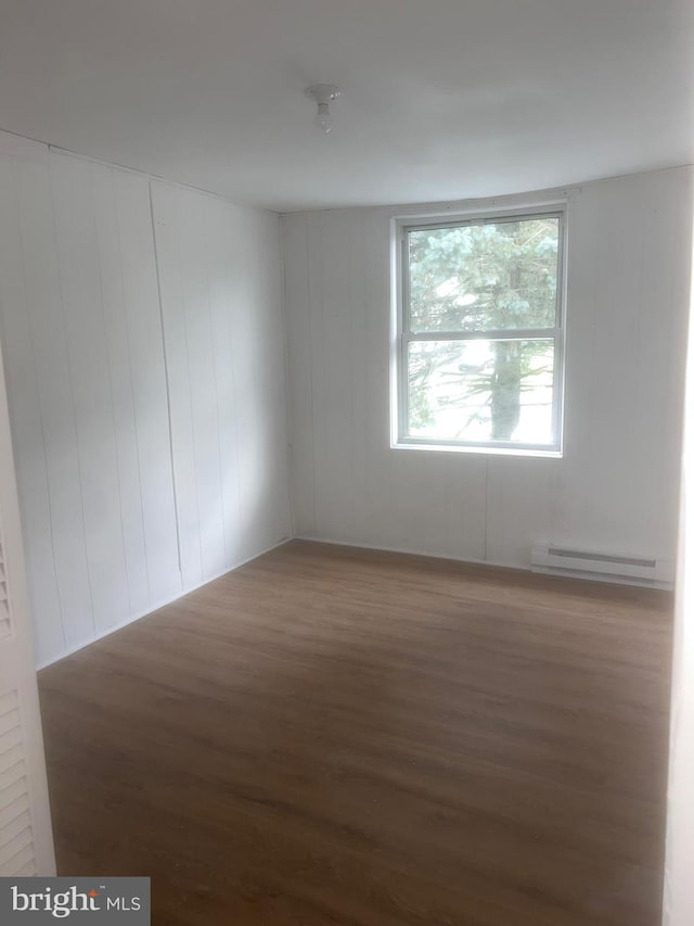 unfurnished room featuring hardwood / wood-style flooring and a baseboard radiator