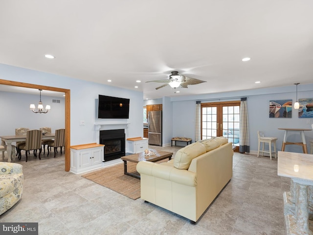 tiled living room featuring ceiling fan with notable chandelier