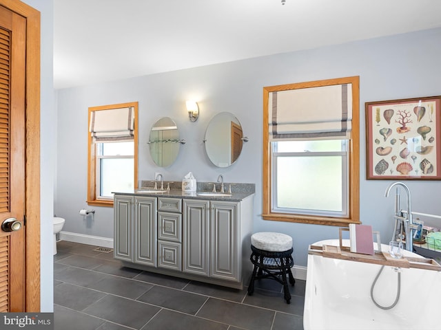 bathroom with double vanity, toilet, and tile patterned floors