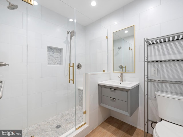 bathroom with toilet, tile walls, an enclosed shower, hardwood / wood-style flooring, and vanity