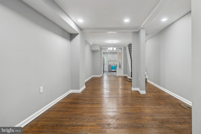 spare room with an inviting chandelier and dark hardwood / wood-style floors