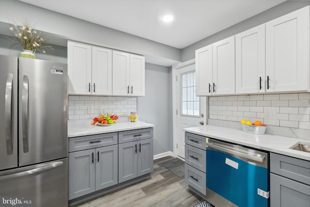 kitchen with stainless steel appliances, gray cabinets, decorative backsplash, and hardwood / wood-style flooring