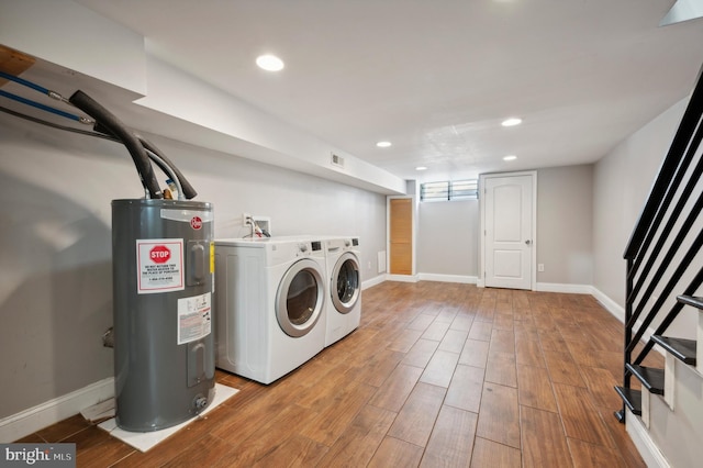 clothes washing area with light hardwood / wood-style floors, water heater, and washer and dryer