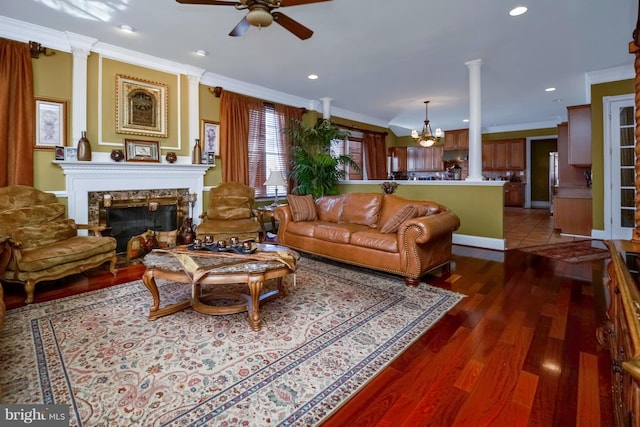 living room with crown molding, decorative columns, wood finished floors, and a premium fireplace