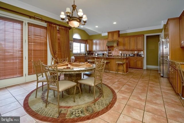 dining space featuring light tile patterned floors, crown molding, sink, a chandelier, and lofted ceiling