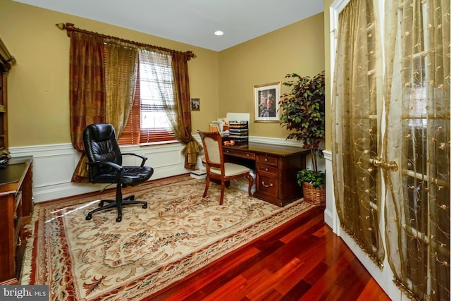 office space featuring dark wood-type flooring, a decorative wall, and wainscoting