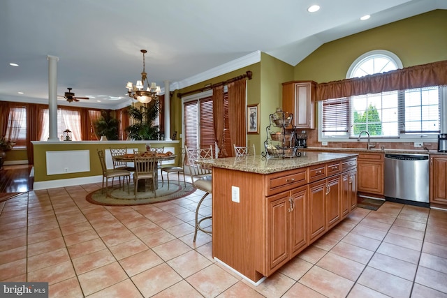 kitchen with light stone countertops, lofted ceiling, light tile patterned flooring, dishwasher, and a center island