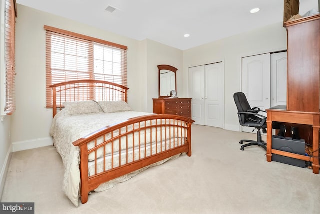 carpeted bedroom featuring recessed lighting, visible vents, multiple closets, and baseboards