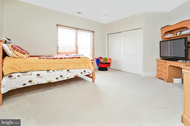 bedroom featuring a closet, baseboards, and light colored carpet