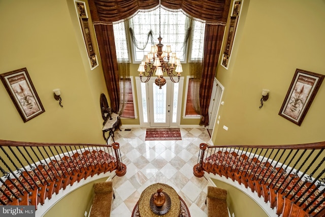 entryway with an inviting chandelier, baseboards, and a towering ceiling