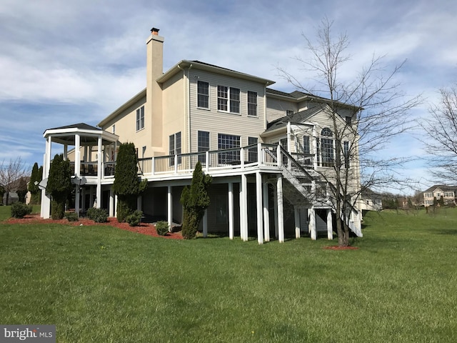 rear view of house featuring a wooden deck, a lawn, and a chimney