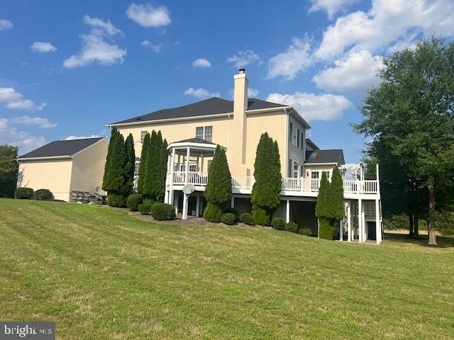 back of house featuring a deck and a lawn