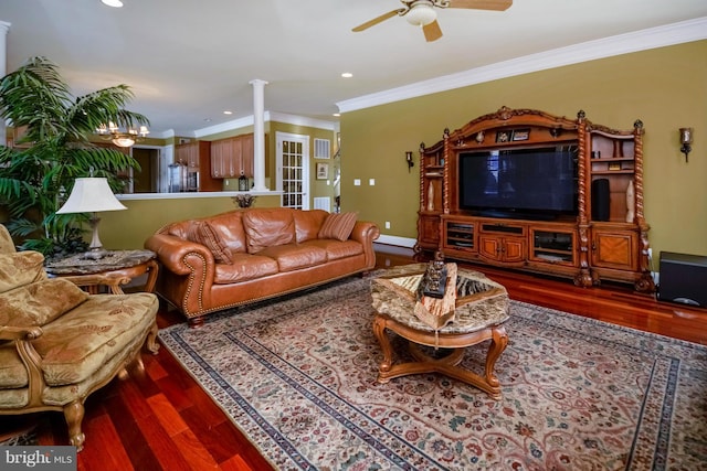 living area featuring ceiling fan with notable chandelier, crown molding, wood finished floors, and baseboards