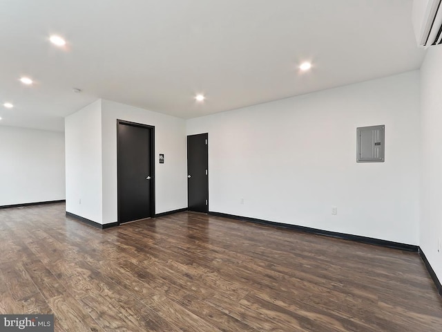 unfurnished room featuring electric panel, dark wood-type flooring, and a wall mounted air conditioner