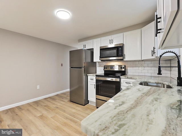 kitchen featuring light wood-type flooring, white cabinets, stainless steel appliances, and sink