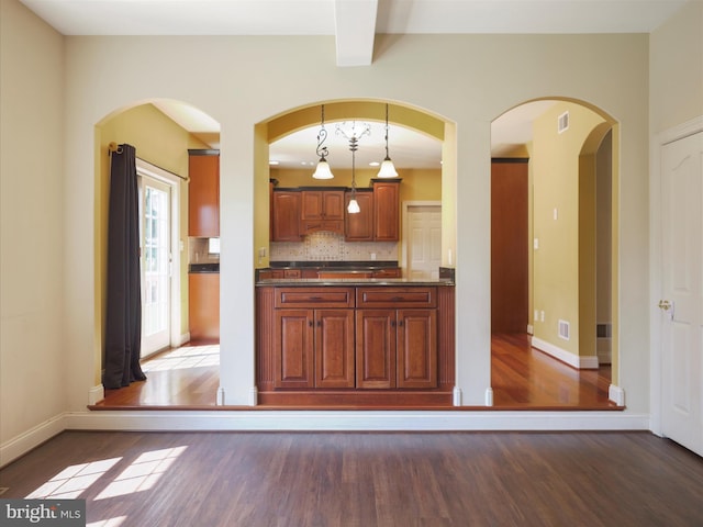 kitchen featuring dark hardwood / wood-style flooring, decorative backsplash, and hanging light fixtures