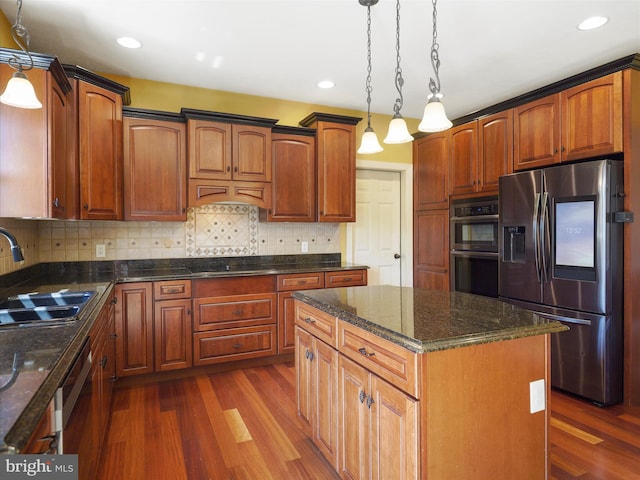 kitchen with dark wood-type flooring, decorative light fixtures, a kitchen island, and stainless steel appliances