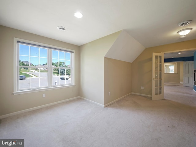 additional living space featuring vaulted ceiling and light carpet