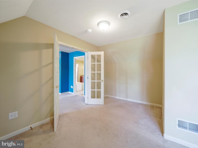 spare room featuring light carpet and vaulted ceiling