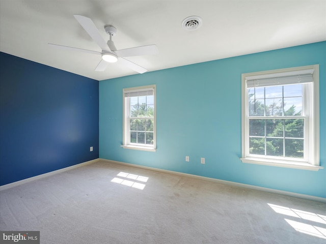 unfurnished room featuring ceiling fan, light carpet, and a healthy amount of sunlight