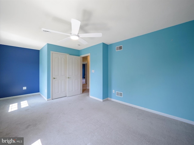 unfurnished bedroom with light colored carpet, ceiling fan, and a closet