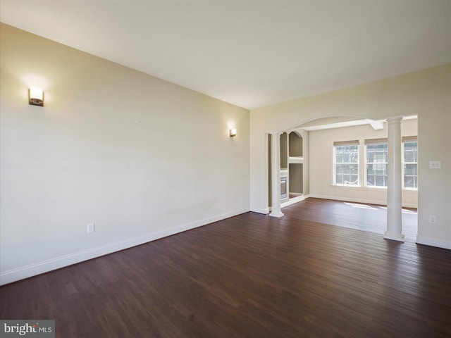 unfurnished room featuring dark wood-type flooring and decorative columns