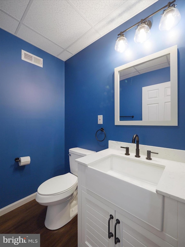 bathroom with a paneled ceiling, toilet, vanity, and hardwood / wood-style flooring