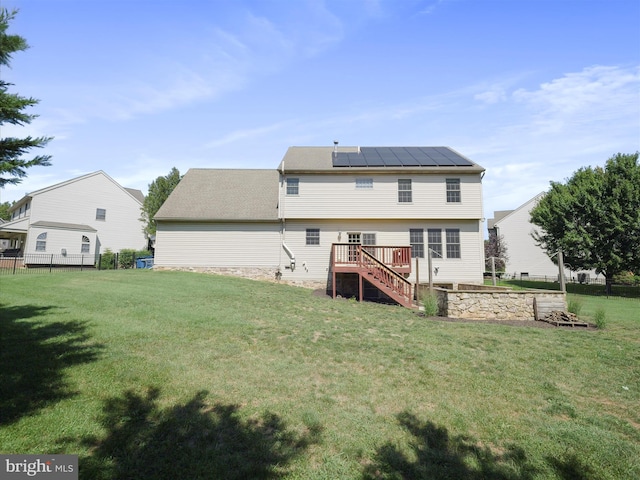 back of house with a yard, solar panels, and a wooden deck