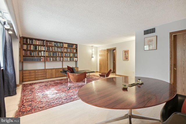 dining area with light hardwood / wood-style flooring and a textured ceiling