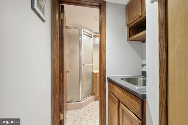 interior space featuring tile patterned floors, vanity, a shower with shower door, and a textured ceiling