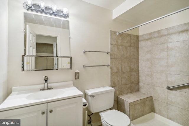 bathroom with toilet, vanity, and tiled shower