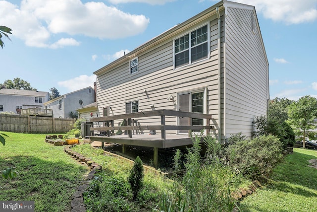 back of house featuring a lawn and a deck