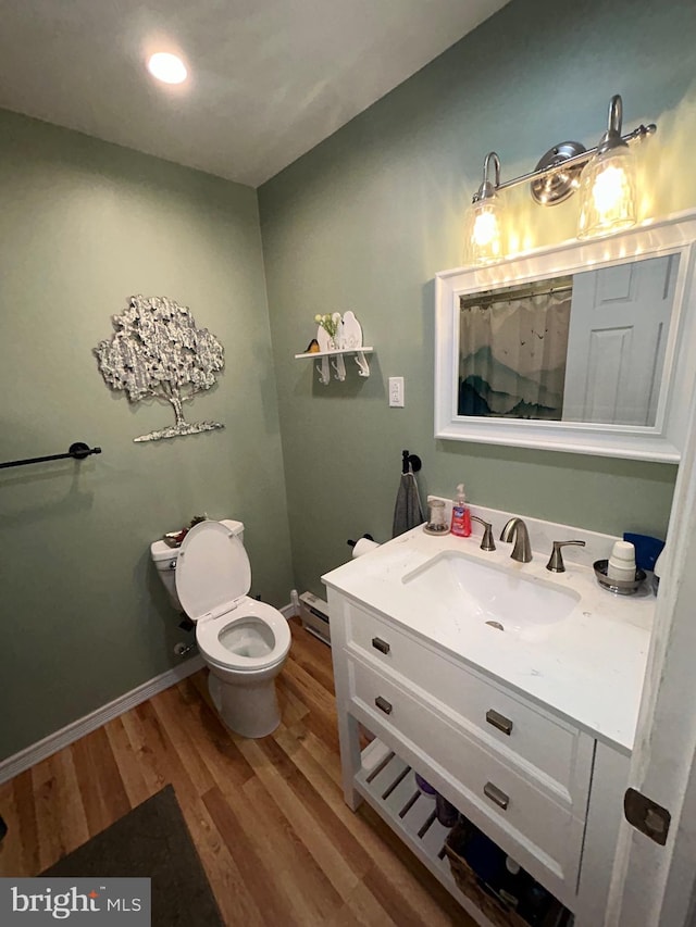 bathroom featuring baseboard heating, wood-type flooring, vanity, and toilet