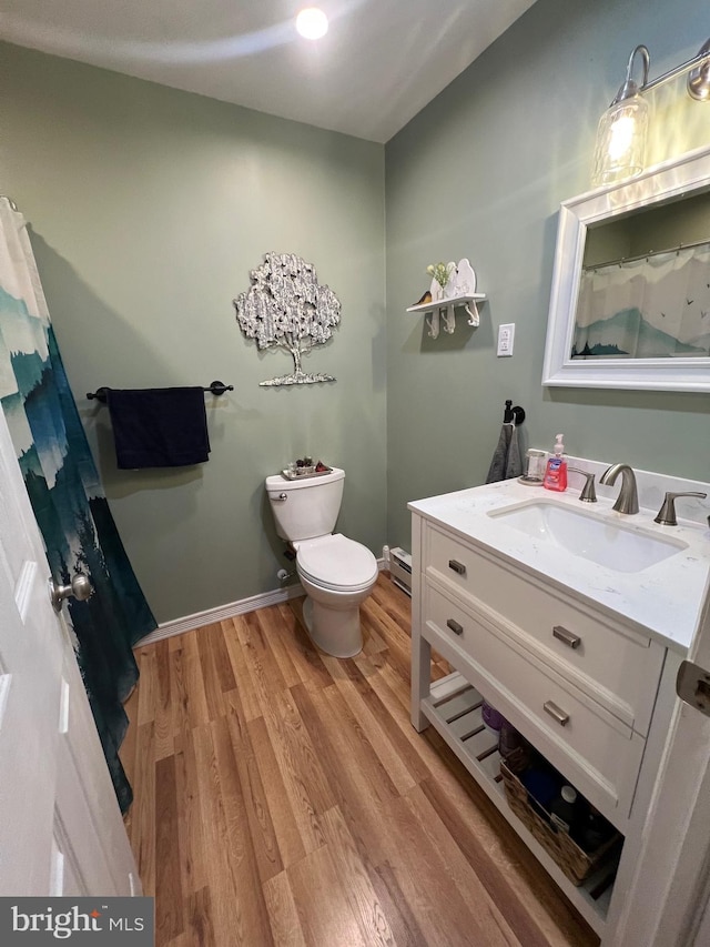 bathroom with toilet, vanity, and hardwood / wood-style flooring