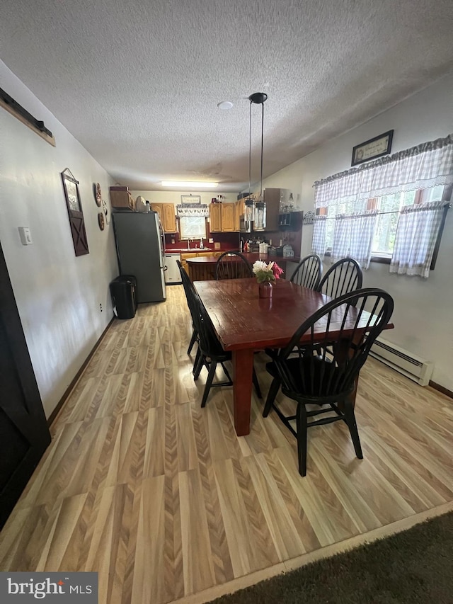 dining area featuring light hardwood / wood-style flooring, sink, and a textured ceiling