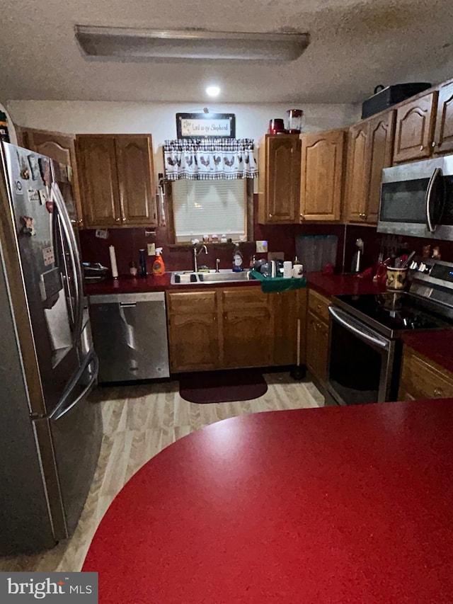 kitchen featuring light wood-type flooring, sink, a textured ceiling, and stainless steel appliances