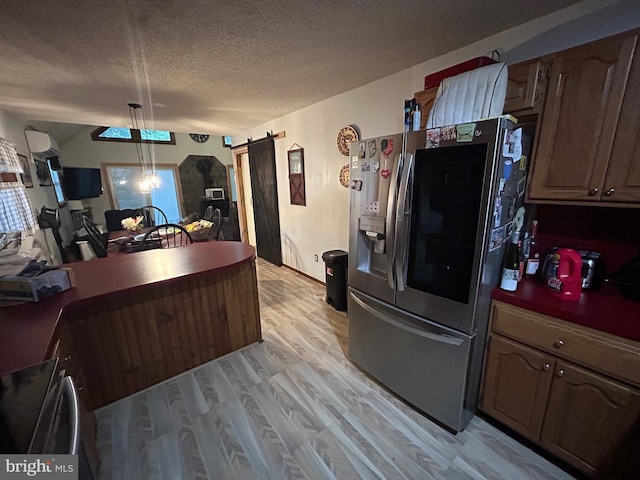 kitchen with a textured ceiling, hanging light fixtures, stainless steel fridge with ice dispenser, light hardwood / wood-style flooring, and a wall mounted AC