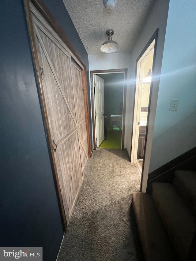 hallway featuring a textured ceiling and carpet flooring