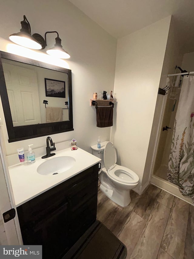 bathroom featuring walk in shower, toilet, vanity, and hardwood / wood-style flooring