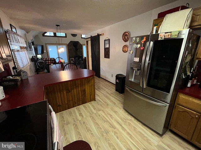 kitchen featuring stainless steel fridge with ice dispenser, light wood-type flooring, a barn door, and decorative light fixtures